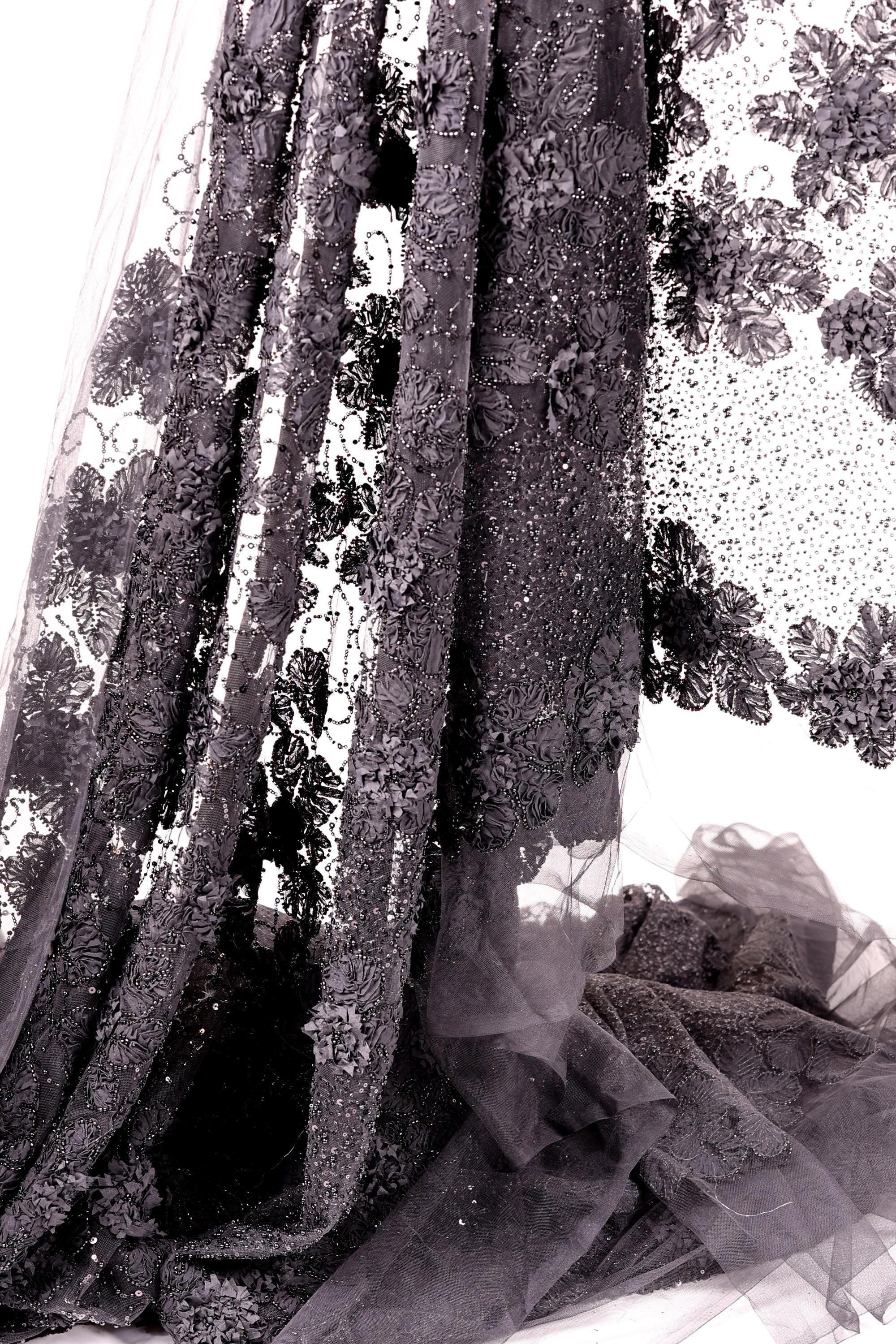 a close-up view of a delicate, intricately embroidered fabric with a floral pattern. The fabric appears to be made of sheer material, giving it a delicate and ethereal appearance. The image is a close-up of the fabric, showcasing its detailed embroidery and the intricate design elements.