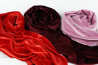 three different colored velvet fabric swatches, including red, burgundy, and pink velvet, arranged on a white background.