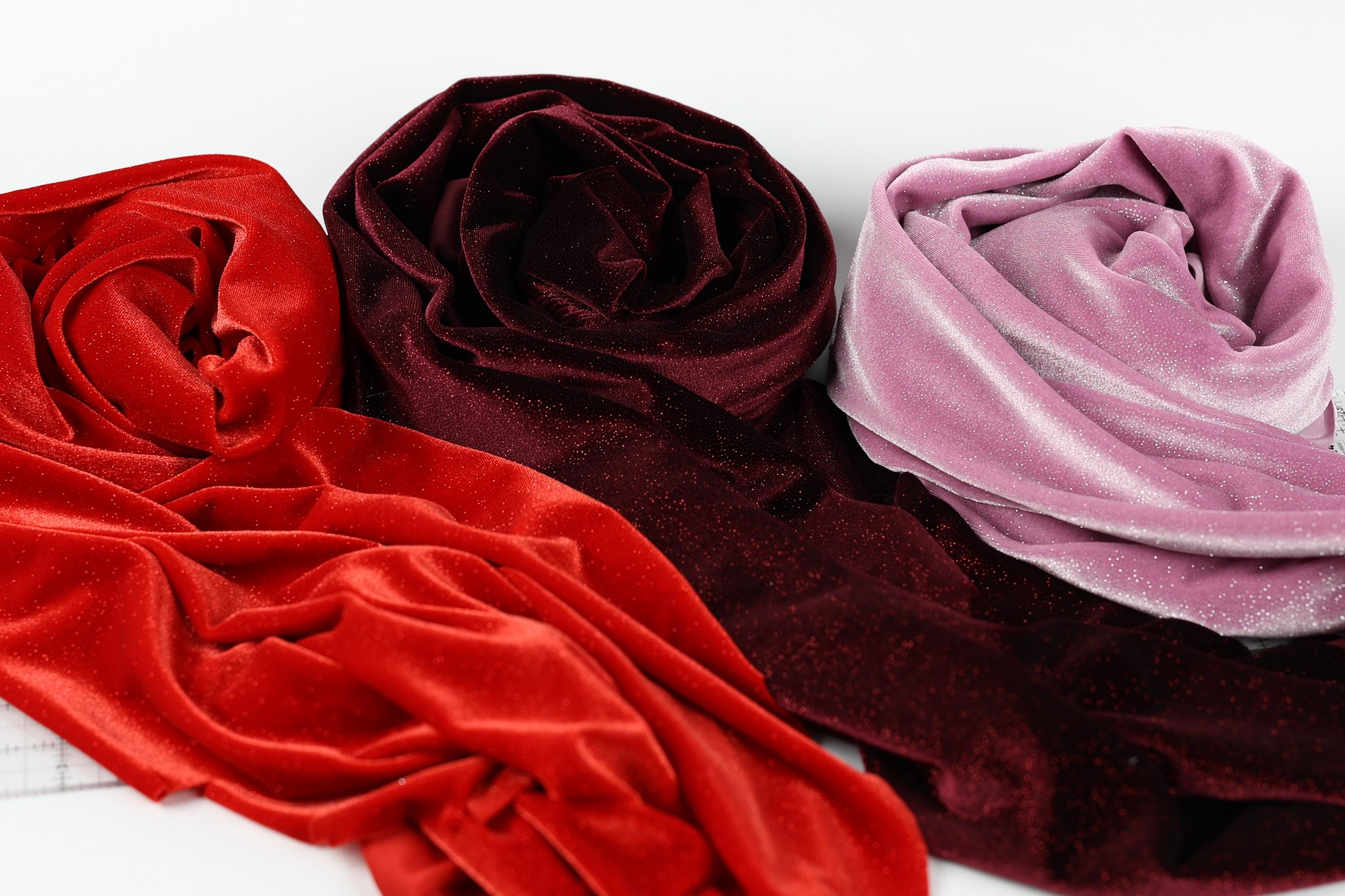 three different colored velvet fabric swatches, including red, burgundy, and pink velvet, arranged on a white background.