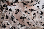 a close-up view of a delicate, sheer fabric with a floral pattern in black and white. The fabric appears to be made of sheer material, giving it a delicate and airy appearance. The floral pattern consists of black flowers interspersed with white flowers, creating a visually striking contrast against the light-colored fabric. The fabric is crumpled, suggesting it may be in the process of being used or displayed.