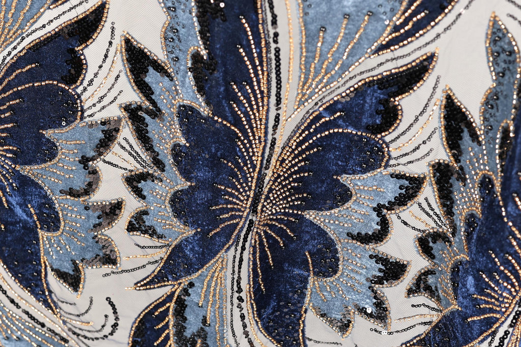 a close-up view of a fabric with a floral pattern, showcasing intricate details and a vibrant mix of blue, black, and gold colors.