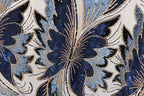 a close-up view of a fabric with a floral pattern, showcasing intricate details and a vibrant mix of blue, black, and gold colors.