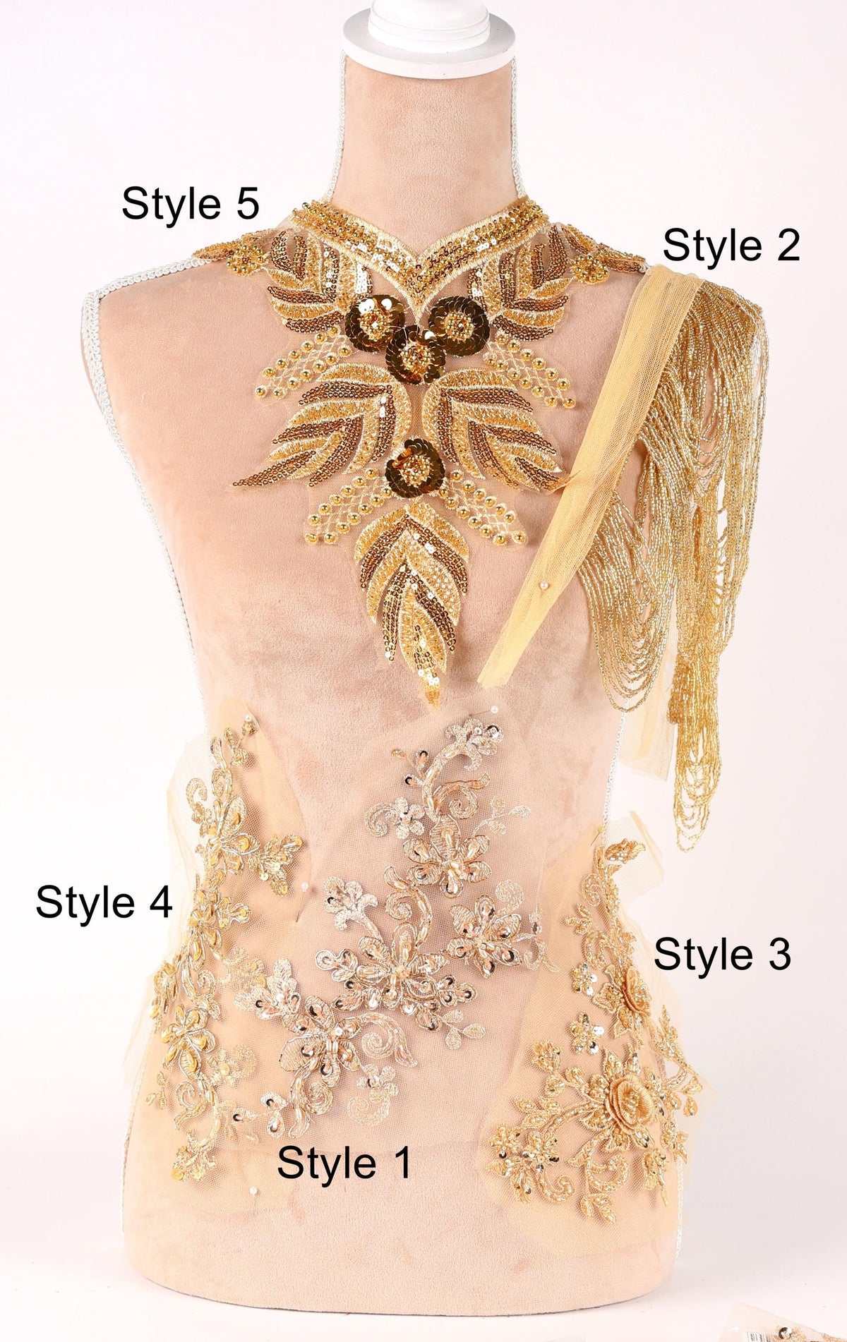 A mannequin wearing a gold and beige embroidered dress with various styles of necklaces and embellishments displayed on it.
