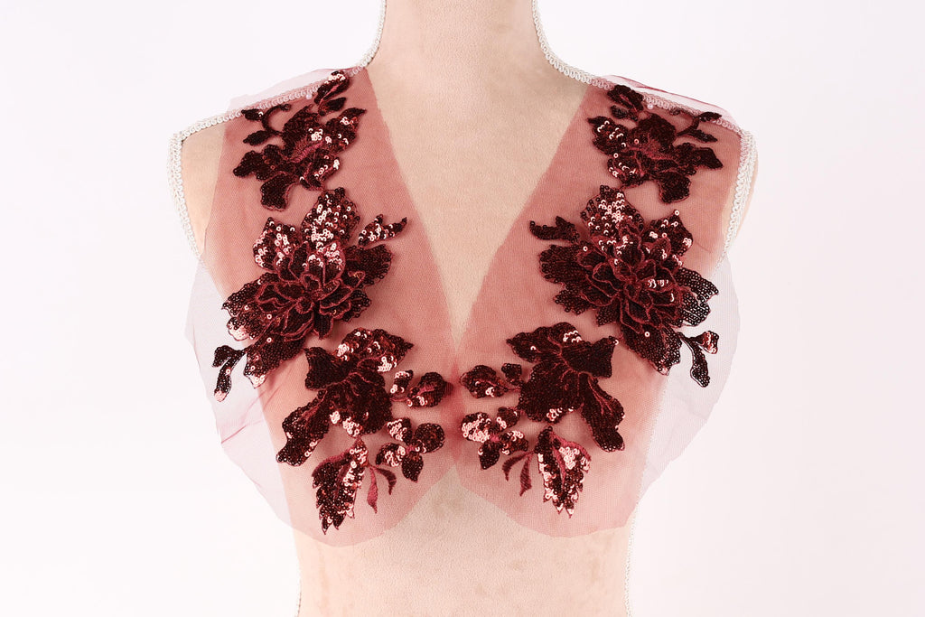 A mannequin wearing a red and black sequin vest with a floral pattern.