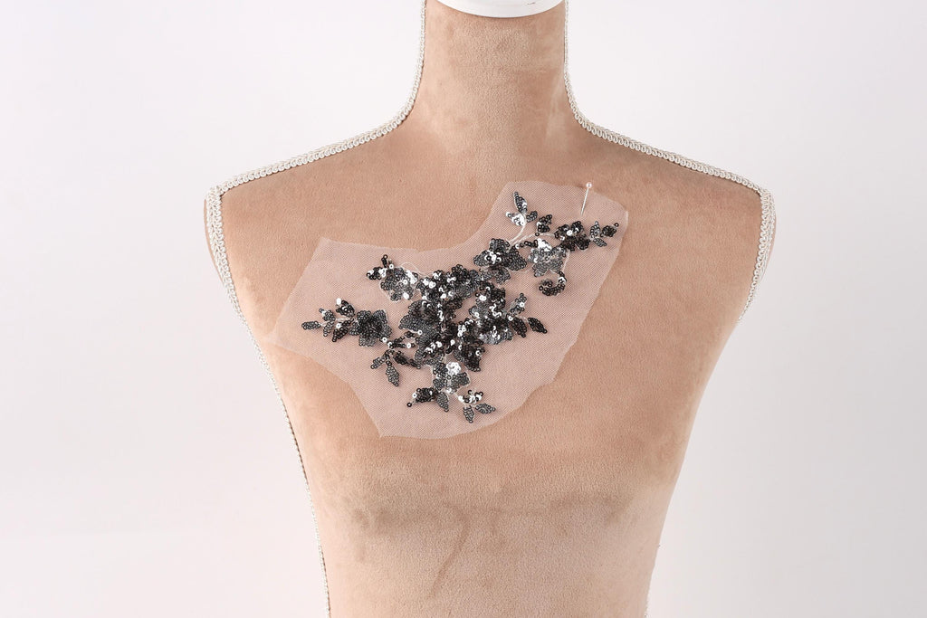 A mannequin torso with a decorative piece of fabric or material attached to it, featuring a floral pattern.