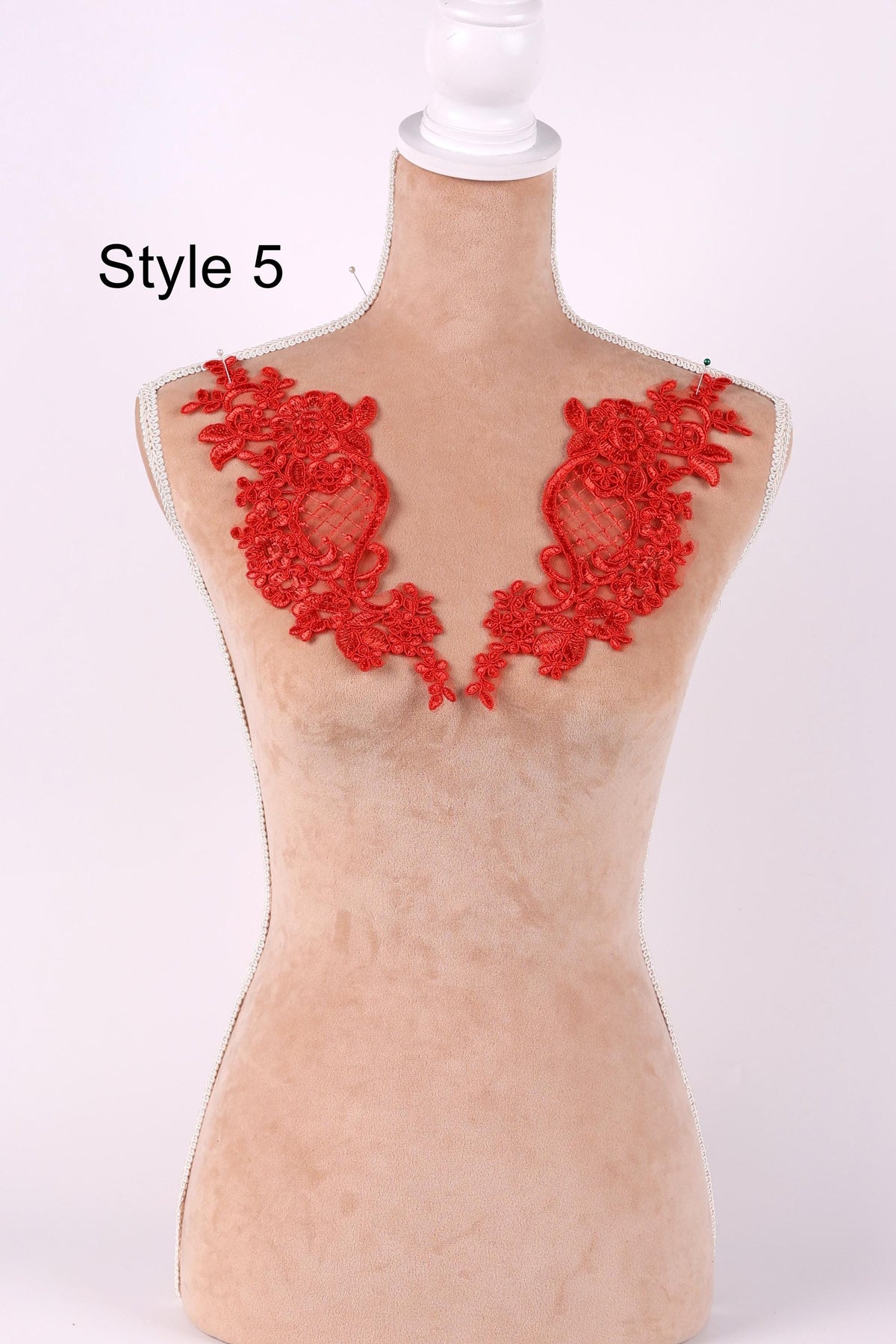A mannequin with red lace or embroidery on its shoulders, displayed against a white background.
