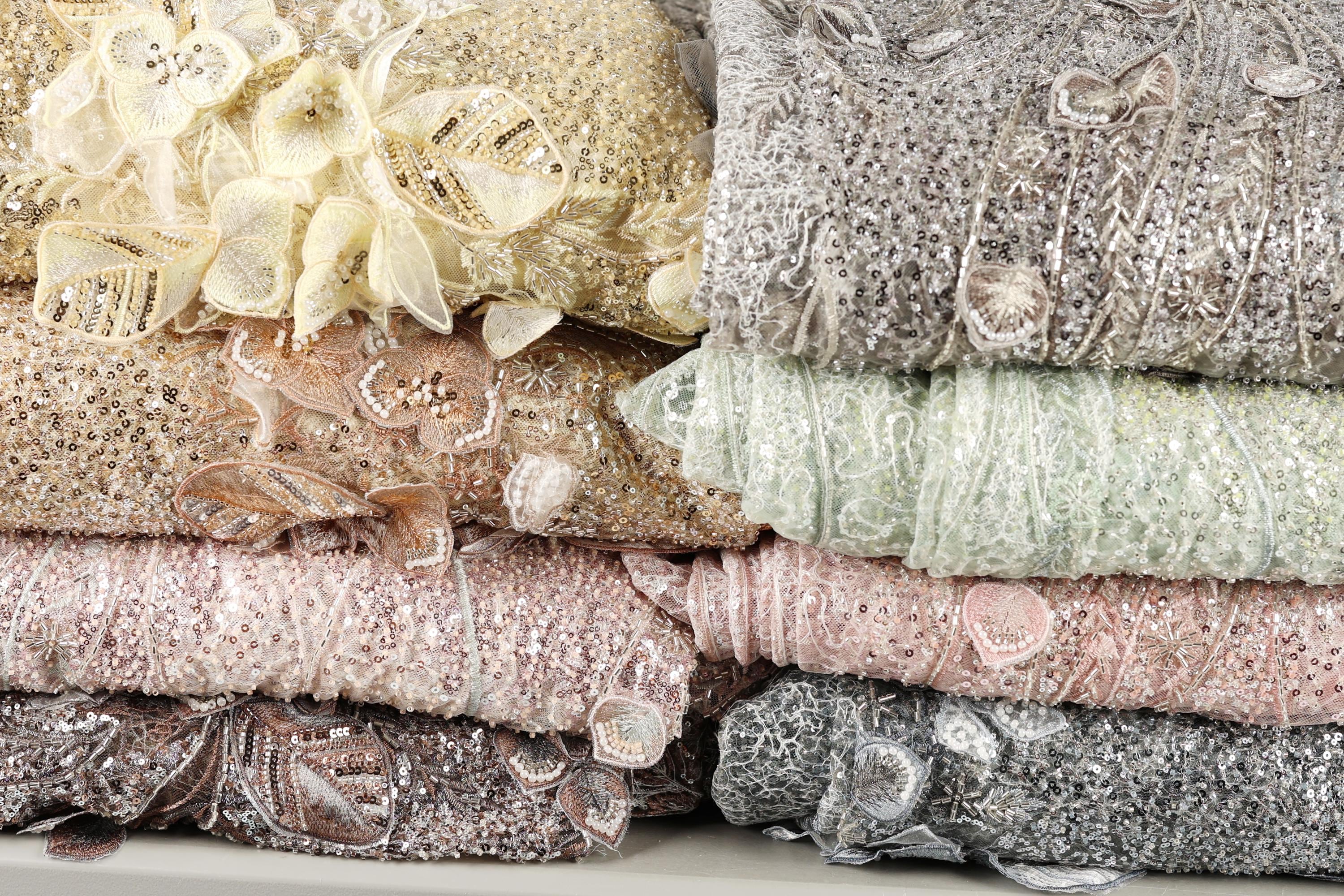 A collection of colorful, intricately designed fabric pieces, including a variety of pastel shades and metallic textures, arranged in a visually appealing manner.