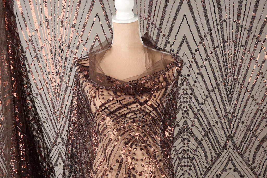 a mannequin wearing a brown sequin dress with a sheer overlay. The dress has a pattern of brown and black sequins, creating a visually striking and elegant design.