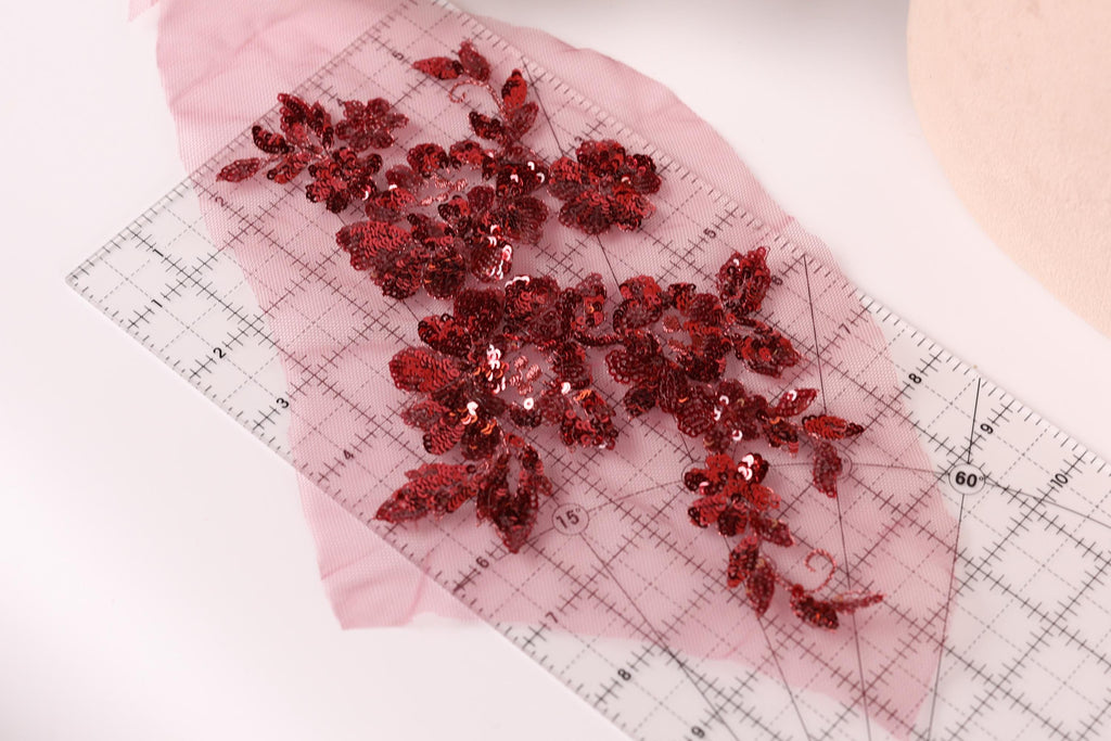 a clear ruler with red sequin flowers placed on it, indicating a craft or sewing project.