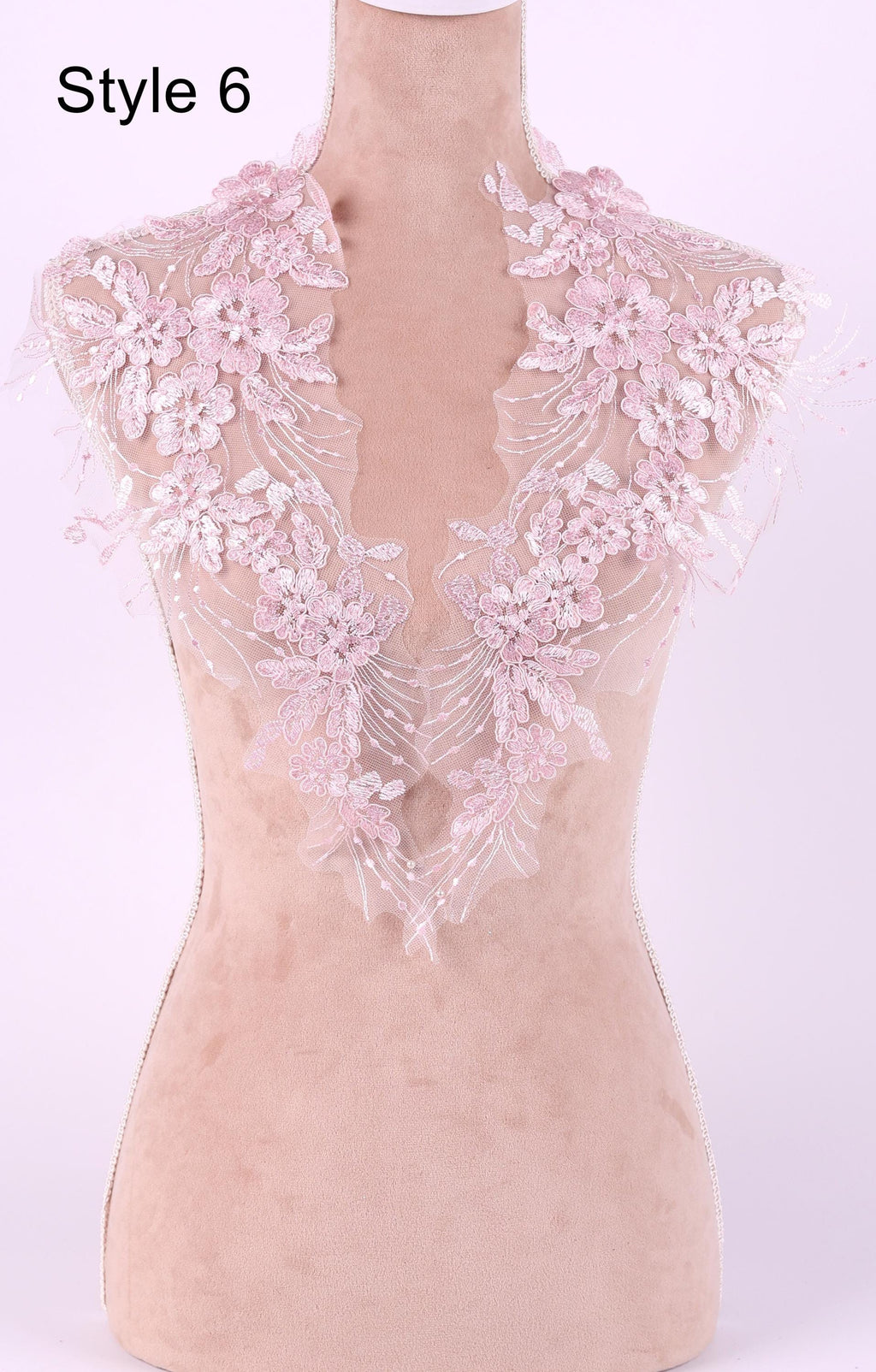 A mannequin wearing a pink lace collar with delicate floral patterns.