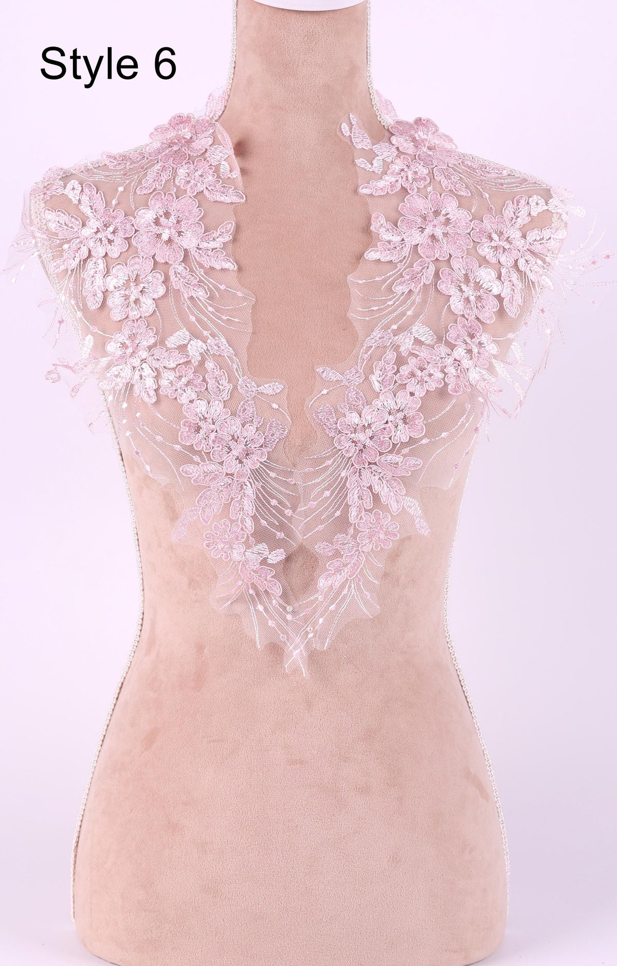A mannequin wearing a pink lace collar with delicate floral patterns.