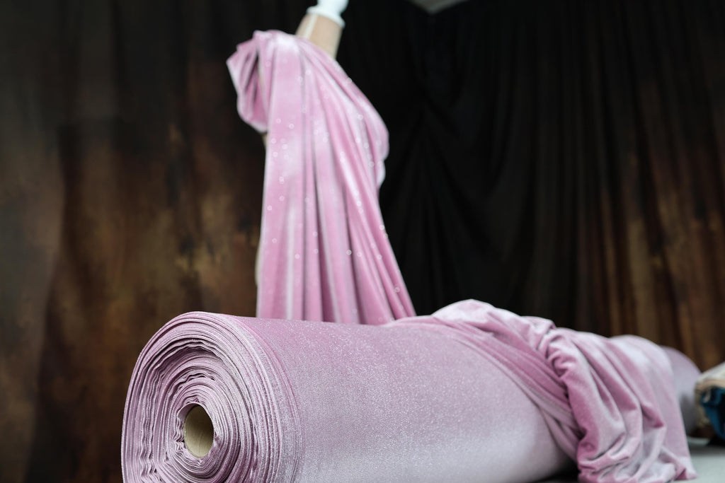 a pink dress laying on top of a roll of fabric