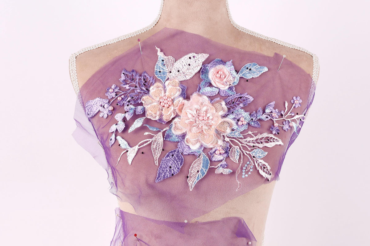 A mannequin with a purple fabric draped over its back, featuring a floral design with pink and purple flowers and leaves.