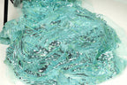 a close-up view of a fabric with a shimmering, sequined texture in shades of blue and green. The fabric appears to be made of a sheer, sheer-like material, giving it a delicate and ethereal appearance.