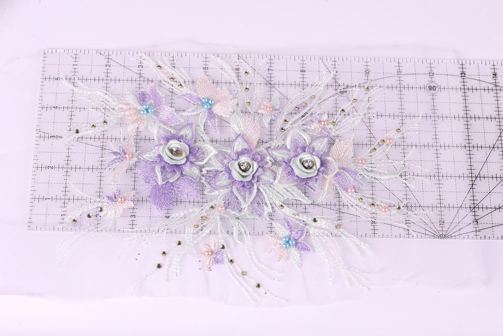 a decorative floral arrangement with purple and white flowers, placed on a transparent ruler against a white background.
