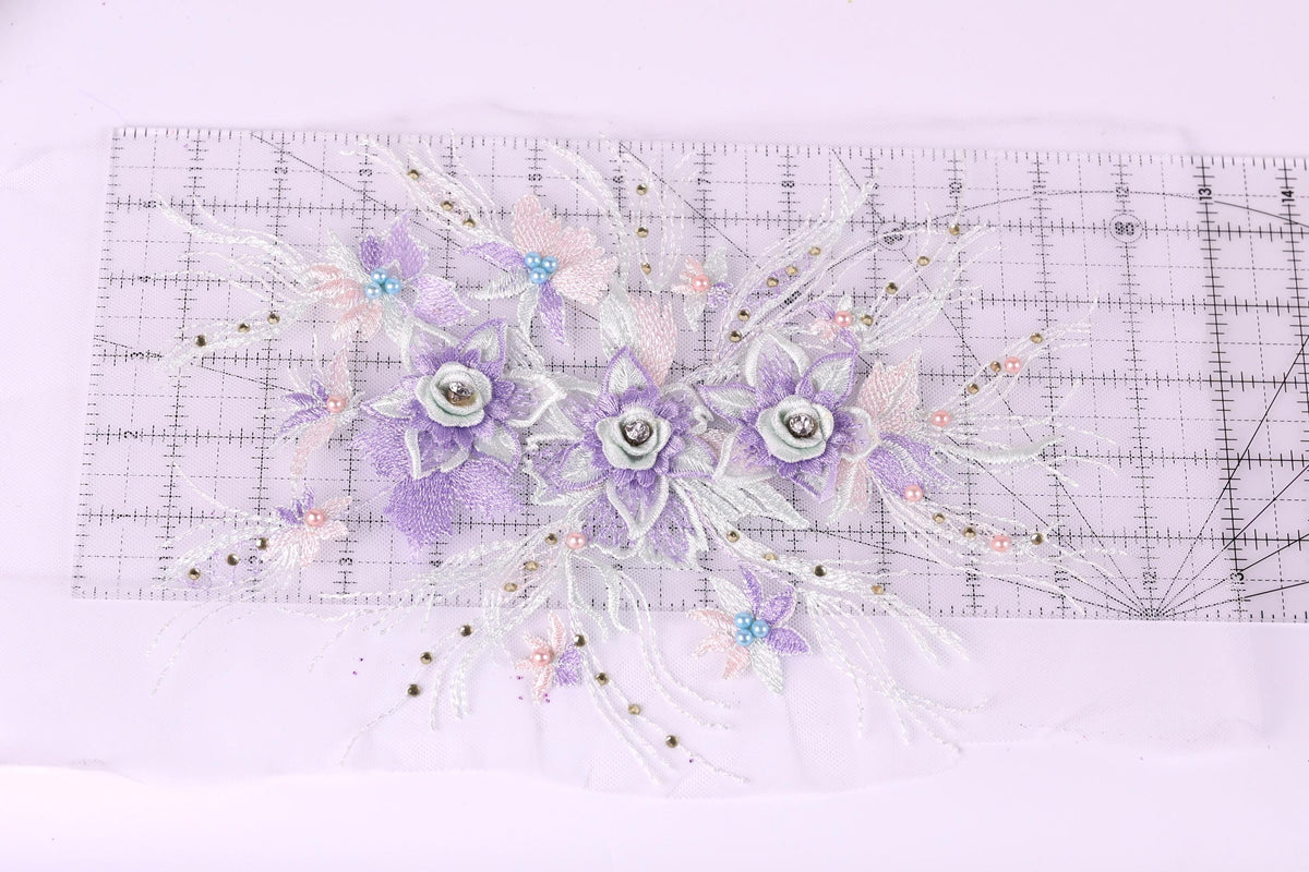 a decorative floral arrangement with purple and white flowers, placed on a transparent ruler against a white background.