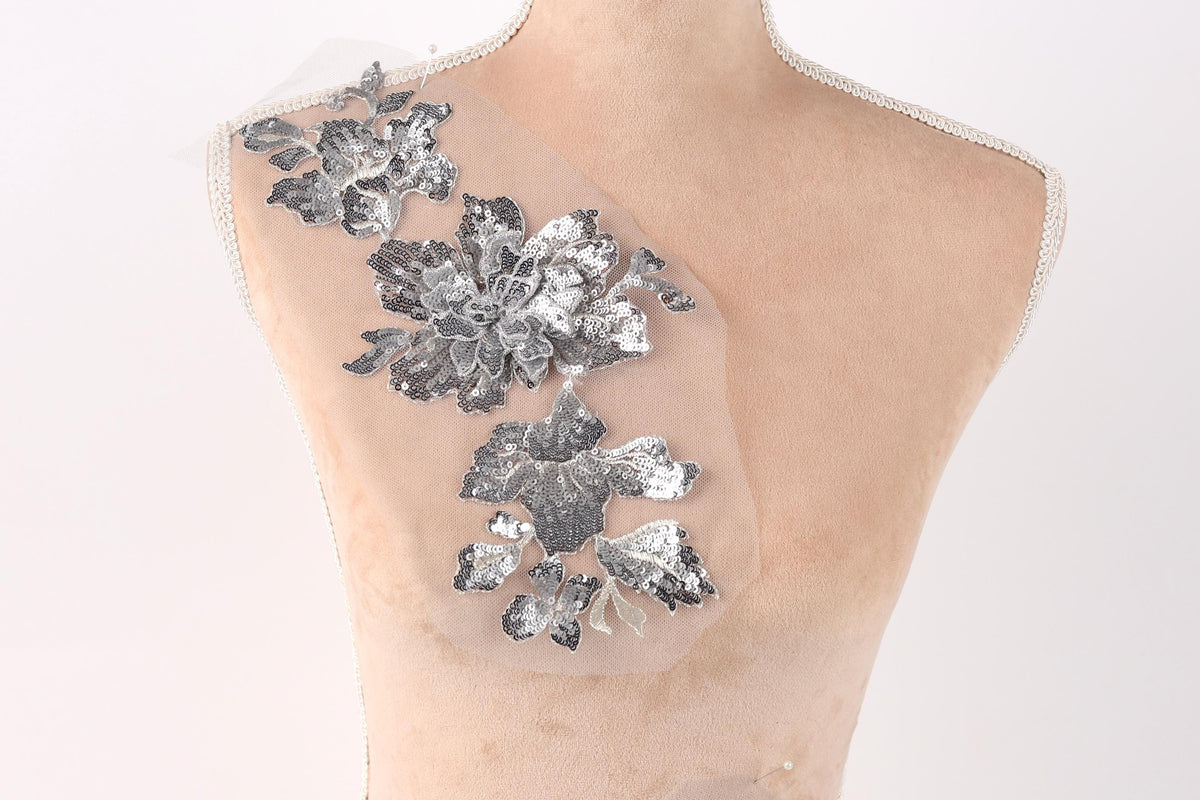 a mannequin torso with a decorative silver flower patch on it.