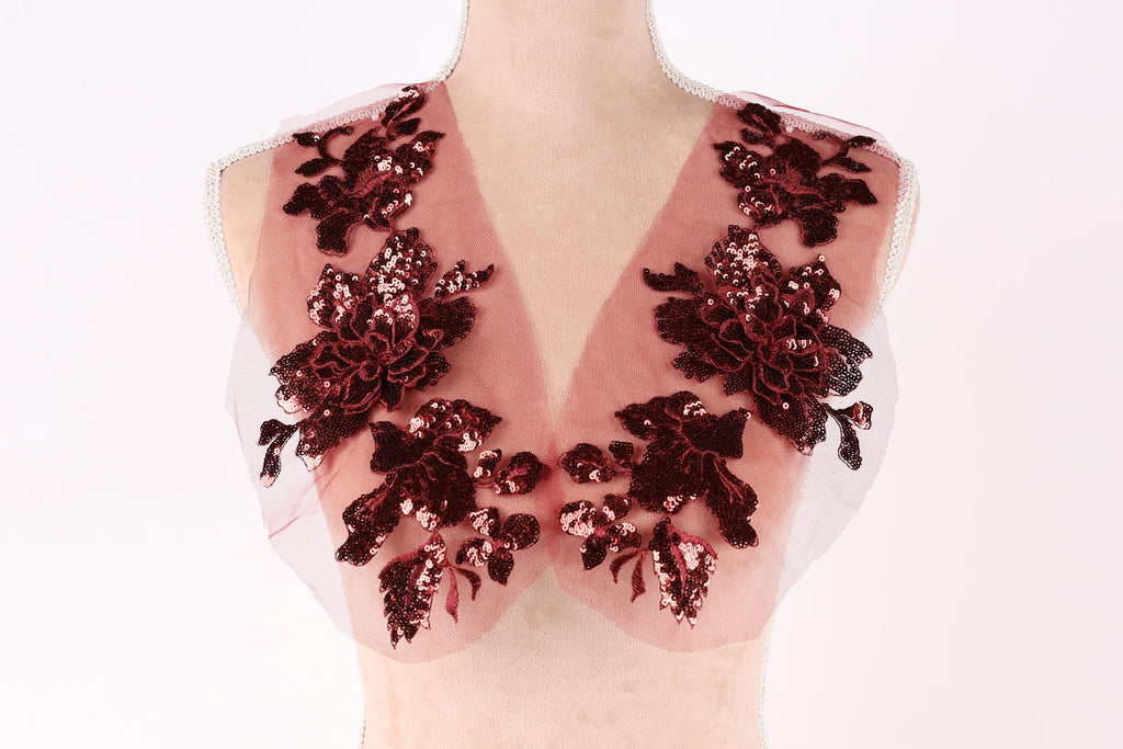 A mannequin wearing a red and black sequin vest with a floral pattern.