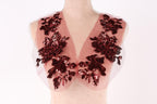A mannequin wearing a red and black sequin vest with a floral pattern.