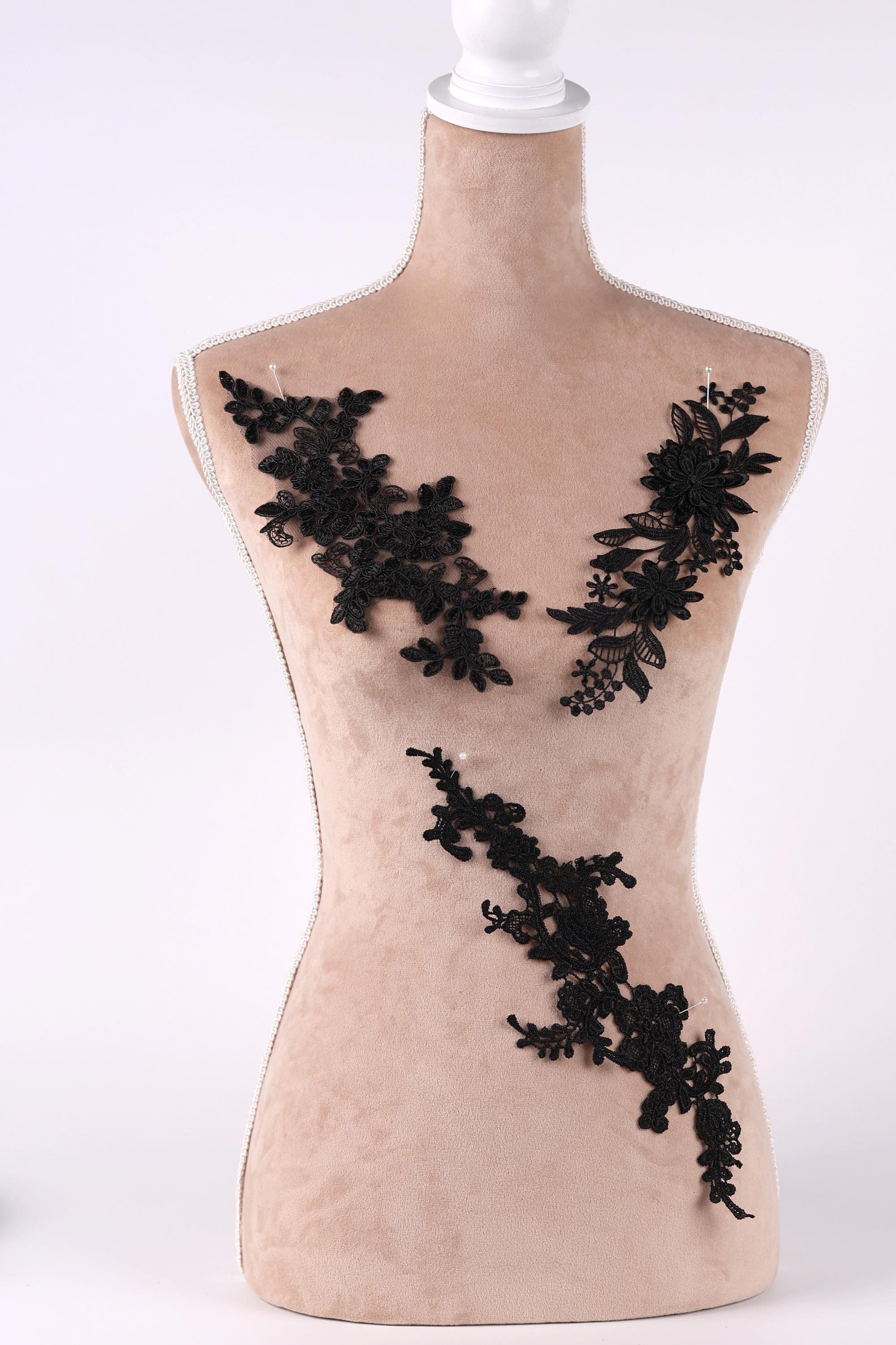A mannequin with a beige body and black lace or floral embroidery on its chest area.