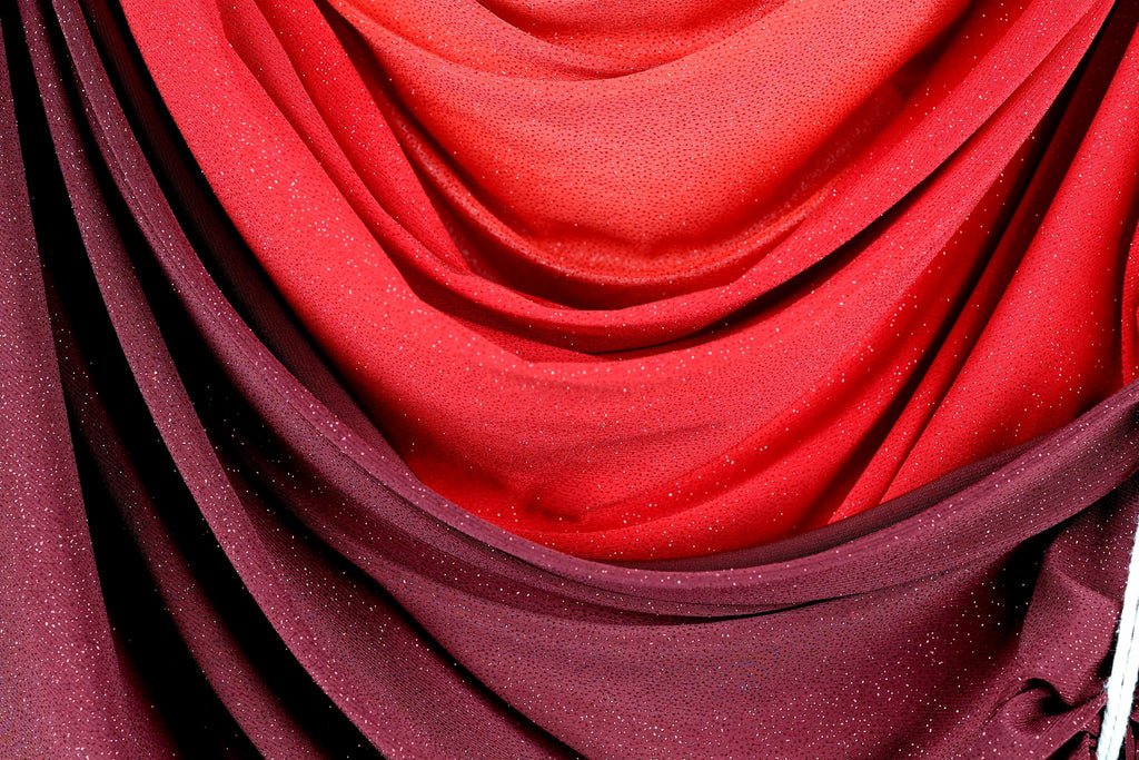 a close-up view of a fabric with a red and purple color scheme, featuring a textured and shiny appearance.