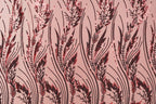a close-up view of a fabric with a repeating pattern of red and black sequin designs. The pattern consists of stylized leaves and stems, creating a visually striking and intricate design.