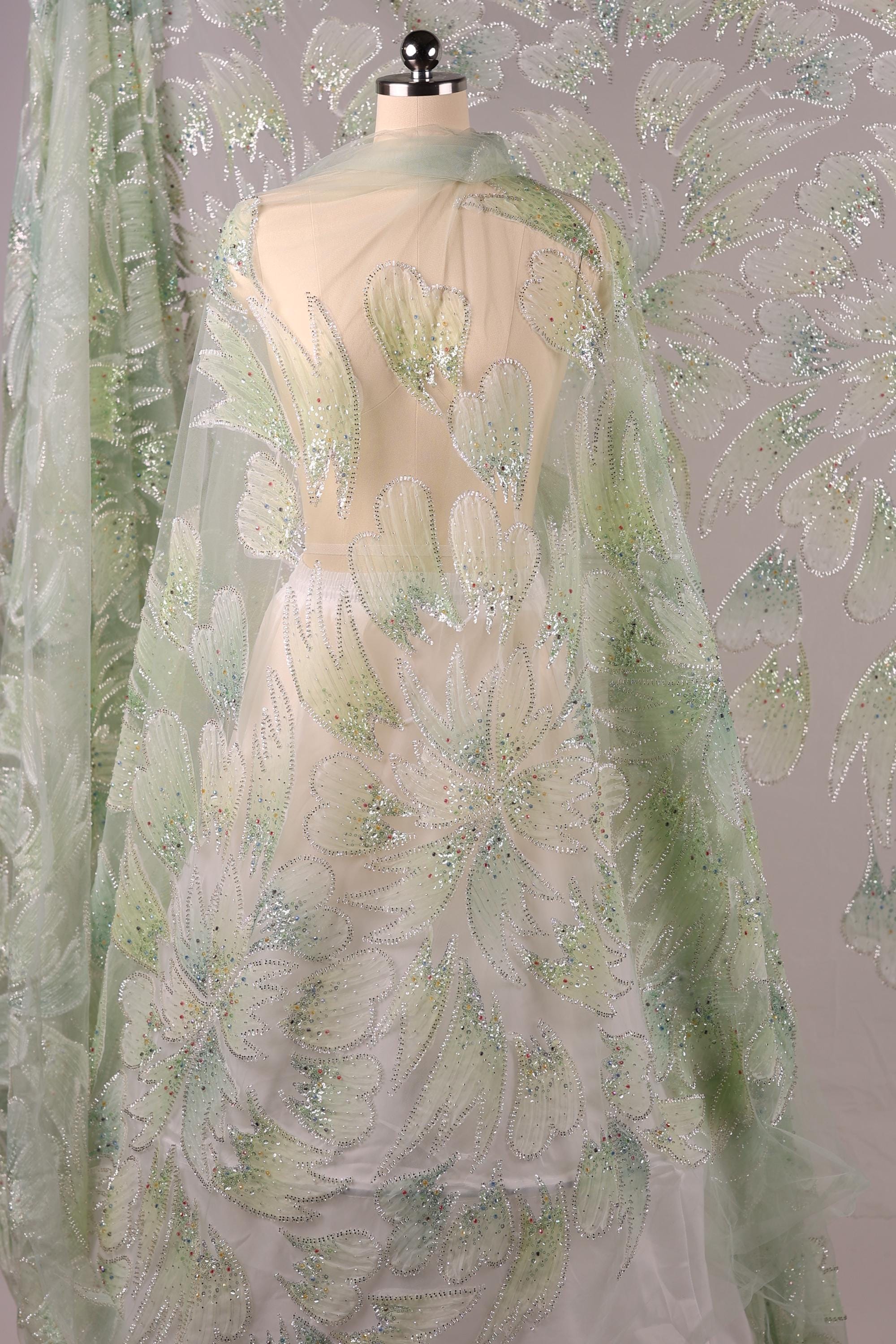 a fabric with a floral pattern, including white and green flowers, and a sheer, transparent overlay.