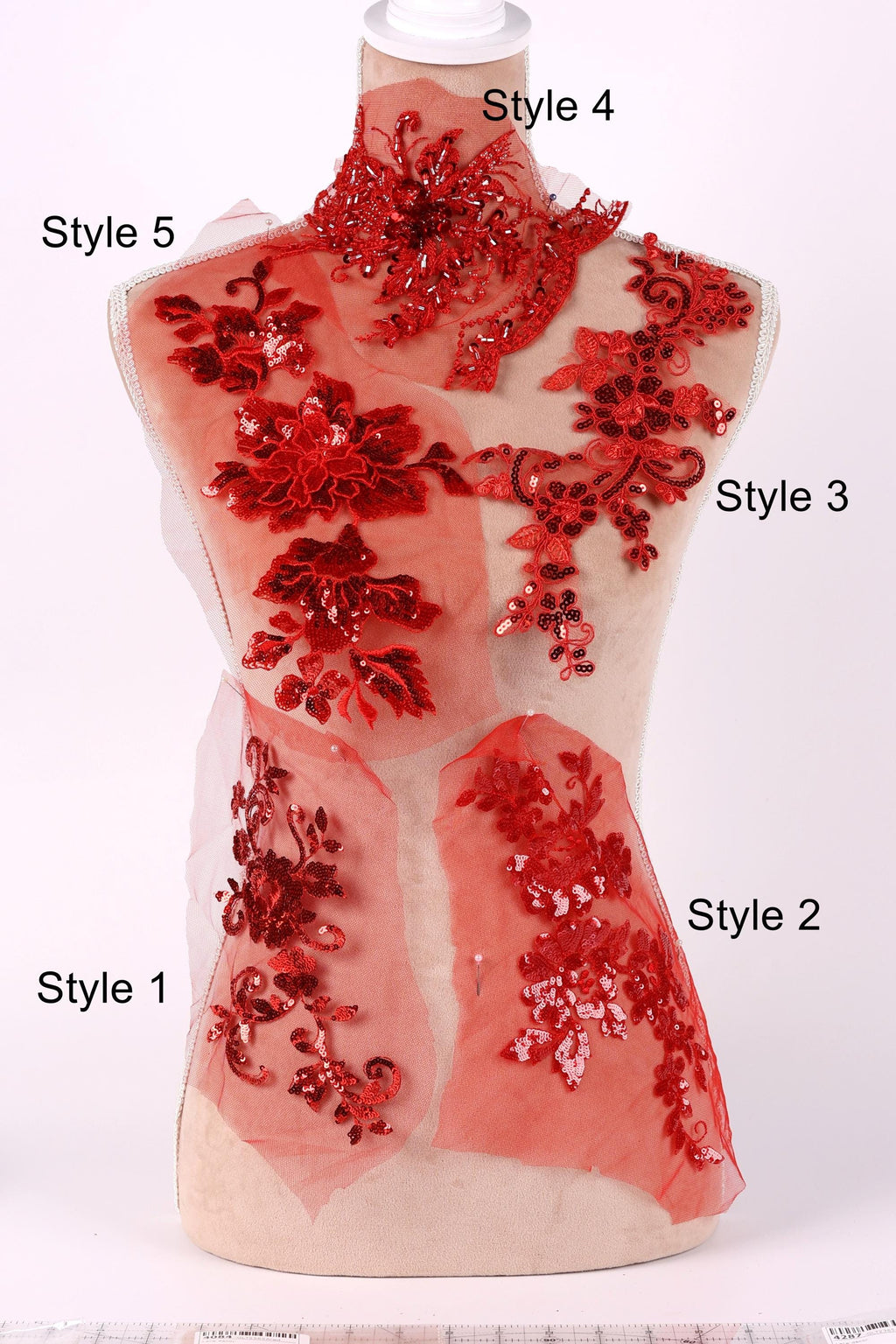 A mannequin with red sequin and floral embellishments on its body, each with a different style number.