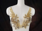A mannequin wearing a white dress with intricate gold and silver embellishments, including flowers and leaves, on the bust area.