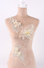 A mannequin wearing a dress with various floral and lace embellishments.