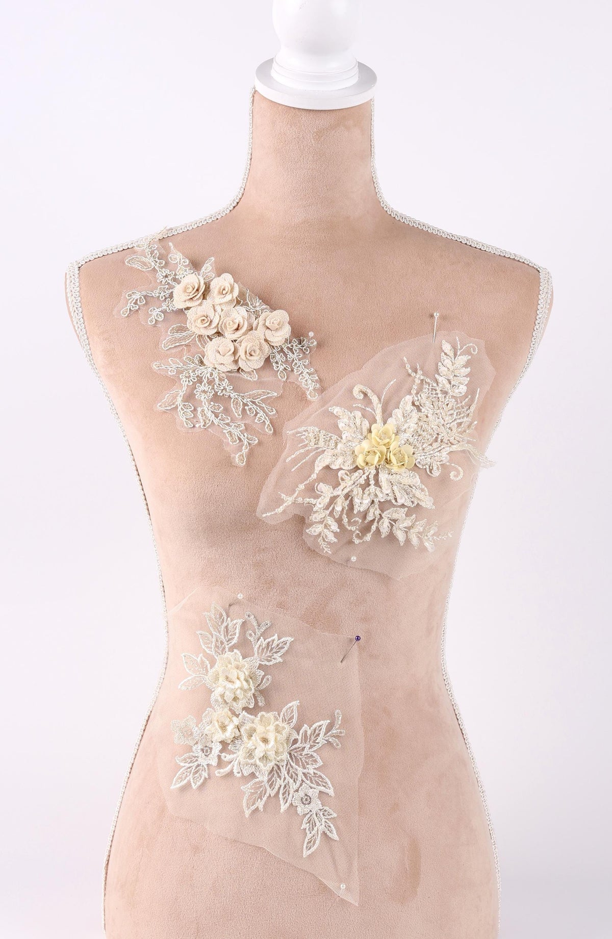 A mannequin wearing a dress with various floral and lace embellishments.