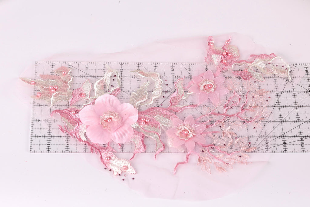 a delicate arrangement of pink flowers and leaves, with a ruler placed in the foreground to provide a sense of scale.
