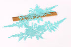 a close-up view of a piece of fabric with intricate blue lace-like patterns, resting on a wooden ruler.