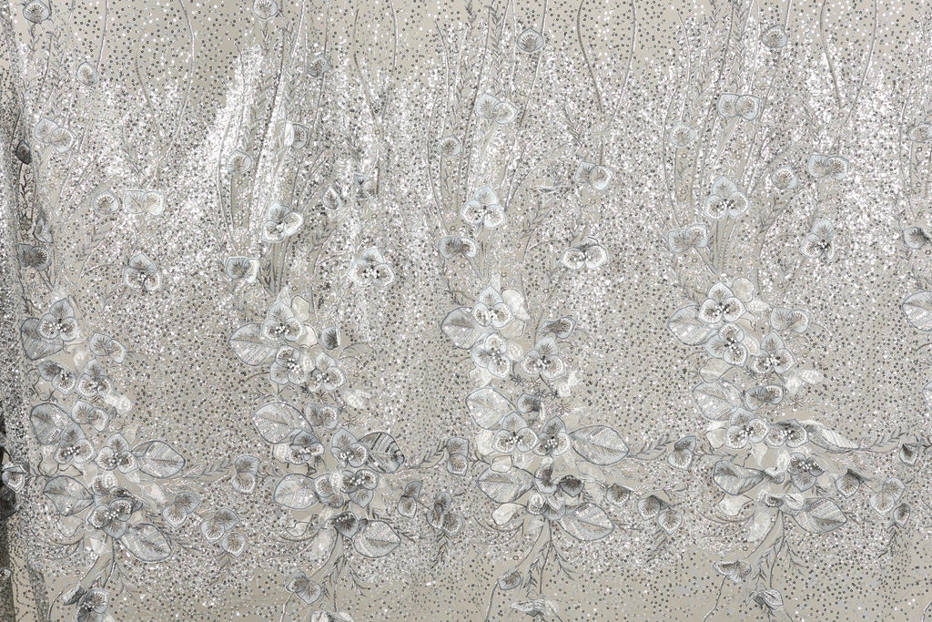 a close-up view of a fabric with a floral pattern, including white and silver sequin details.