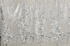 a close-up view of a fabric with a floral pattern, including white and silver sequin details.