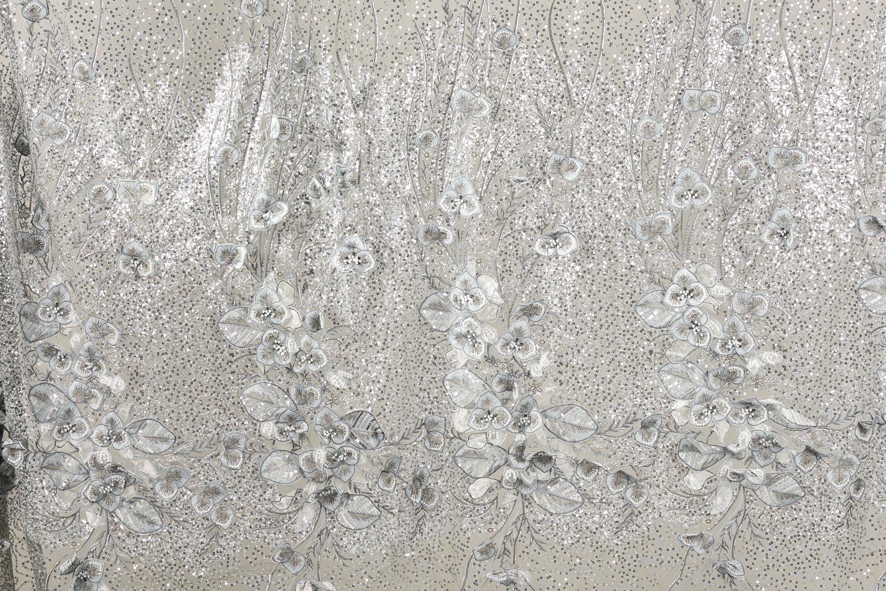 a close-up view of a fabric with a floral pattern, including white and silver sequin details.