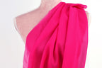 A mannequin wearing a pink, draped fabric draped over its shoulder.