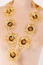 A close-up image of a necklace with numerous gold-colored flower-shaped embellishments.