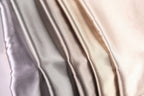 A close-up image of a fabric with a gradient of colors, transitioning from a light gray to a darker gray to a beige.