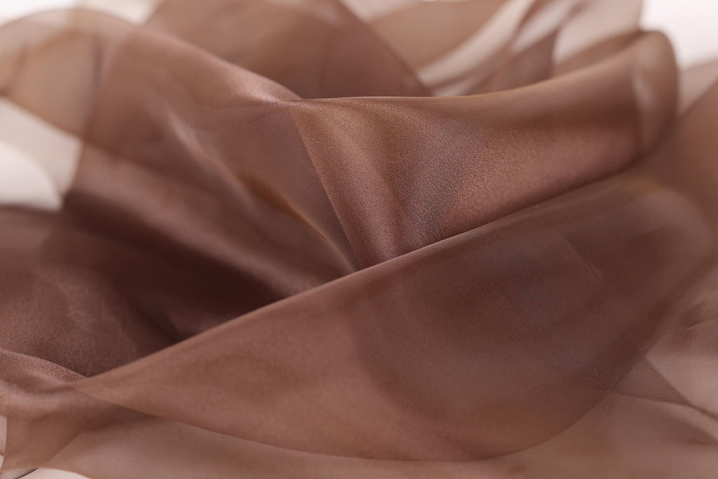 The image is a close-up of a brown fabric, possibly silk or chiffon, with a soft, flowing texture.