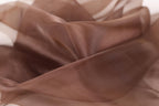 The image is a close-up of a brown fabric, possibly silk or chiffon, with a soft, flowing texture.