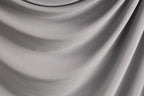 The image is a close-up of a gray fabric, possibly a piece of clothing or a textile. The fabric has a smooth, flowing texture and appears to be made of a soft, shiny material.