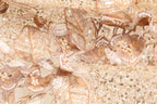 The image is a close-up of a fabric with intricate gold and white embroidered designs, including flowers and leaves. The fabric appears to be a delicate and ornate material, possibly used for clothing or other decorative purposes.
