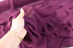 a woman's hand holding onto a purple dress