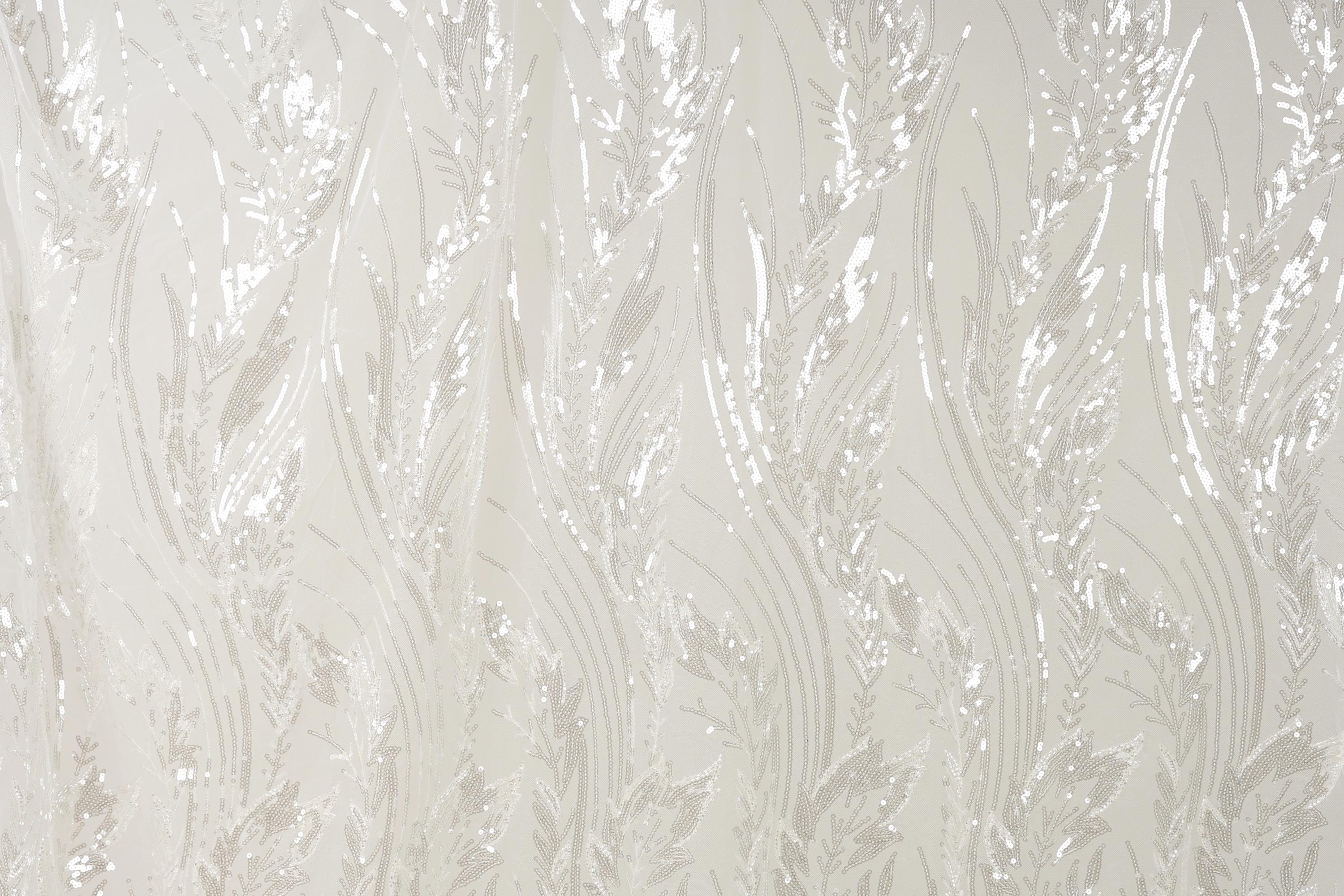 a close-up view of a fabric with a repeating pattern of white and beige lines and shapes, resembling the appearance of grass or leaves.