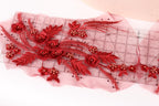 a close-up view of a delicate red floral embroidery on a piece of fabric, with a ruler visible in the background.