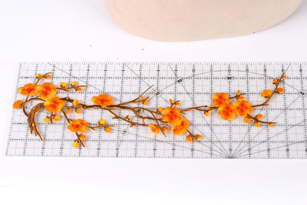 a close-up view of a clear ruler with orange flowers and branches placed on it.