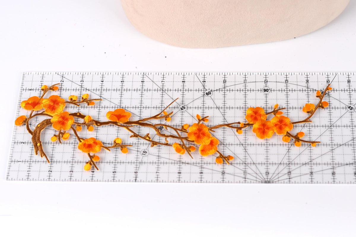 a close-up view of a clear ruler with orange flowers and branches placed on it.