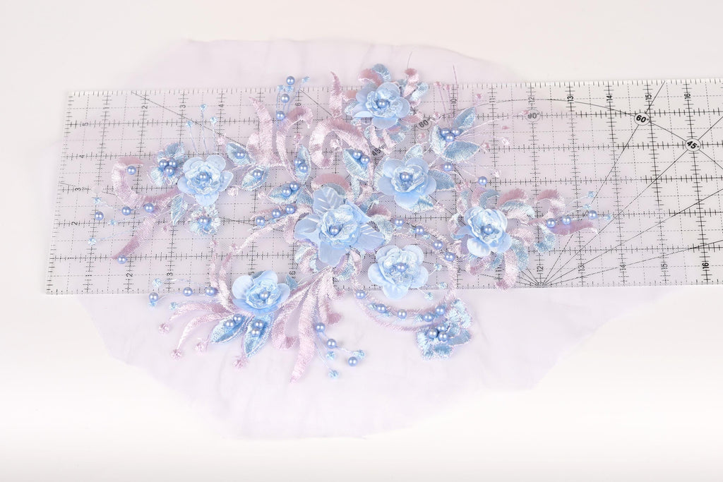 a delicate floral arrangement with blue flowers and beaded accents, placed on a transparent surface.