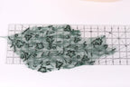 a transparent green fabric with numerous small black sequins or beads scattered across it, placed on a transparent ruler or measuring mat.